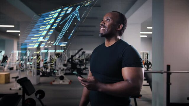 Man in gym checking fitness application in smartphone, personal program online watch with body health indicator projecting hologram, checking calories burn.Future technology new futuristic concept.