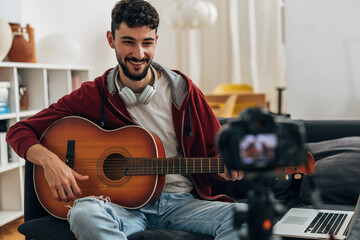 A musician is recording himself playing guitar