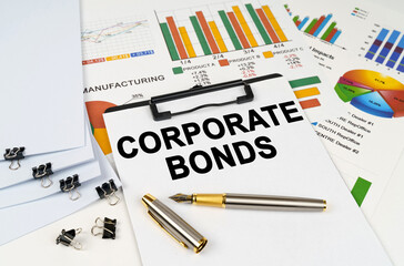 On the table among financial graphs and charts lies a tablet with the inscription - Corporate Bonds