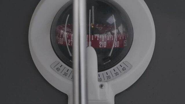 Close-up shot of a compass of a sailing boat. Sailing boat navigation. Compass and steering wheel close up.
Sailing boat navigation device. Sailing in the right direction. Steering wheel turning.  