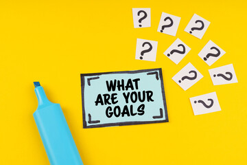 On the yellow surface is a marker, question marks and a sticker with the inscription - WHAT ARE YOUR GOALS