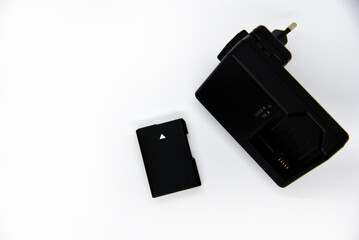 Black charger and battery for cameras. Charger and battery on a white background. Black accessories for the camera.