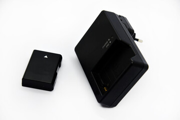 Black charger and battery for cameras. Charger and battery on a white background. Black accessories for the camera.