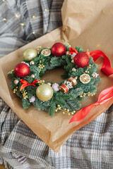Beautifully decorated Christmas wreath in wrapping paper lies on a sofa. Christmas preparation.