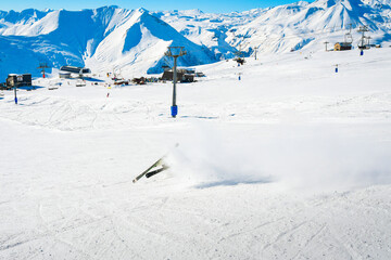 Dynamic picture of a skier on the piste in Alps fall down hard in snow. Active winter holidays,...