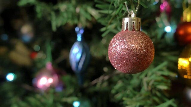 Close up shot of a Christmas ball, hanging on a Christmas tree. Christmas lights shining in the blurred background. Copy space for text mockup, "Merry Christmas" or "Happy New Year". Seamless looping