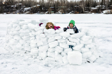 Children playing in a snow fort on frozen Lake Wabamun; Wabamun, Alberta, Canada