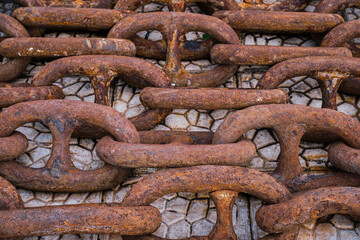 Old rusty ship's chain on the pier, top view. Idea for the background, the concept of shipping and recycling of materials