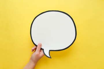 Speech bubble in hand on a yellow background. Comic cloud with a place for text