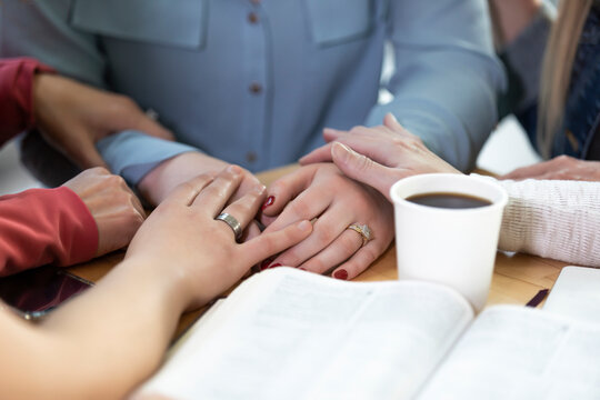 A group of women gathered together praying for one of the women after a Bible study in a coffee shop at a church; Edmonton, Alberta, Canada