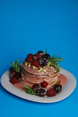 sweet delicious fragrant pink cupcakes in the shape of a heart and round with pink icing on top and decorated with blackberry raspberries and a sprig of rosemary on a blue background. for signage menu