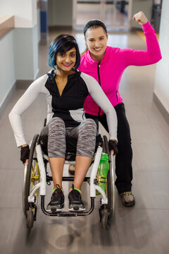 A paraplegic woman and her trainer pose for the camera while in a hallway in a recreational facility: Sherwood Park, Alberta, Canada