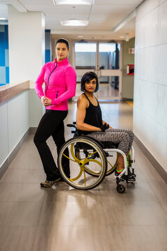 A paraplegic woman and her trainer pose for the camera while in a hallway in a recreational facility: Sherwood Park, Alberta, Canada