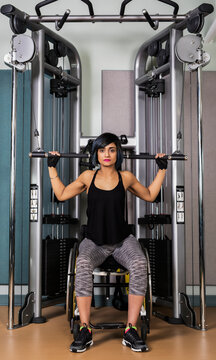A paraplegic woman working out using a lat pull down machine in a fitness facility; Sherwood Park, Alberta, Canada