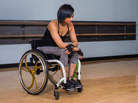 A paraplegic woman looking discouraged while taking a break from working out in a recreational facility: Edmonton, Alberta, Canada