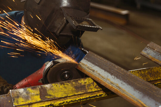 Tradesman grinding a steel beam in a metal fabrication plant; Innisfail, Alberta, Canada