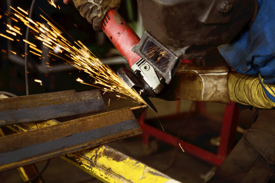 Tradesman grinding a steel beam in a metal fabrication plant; Innisfail, Alberta, Canada