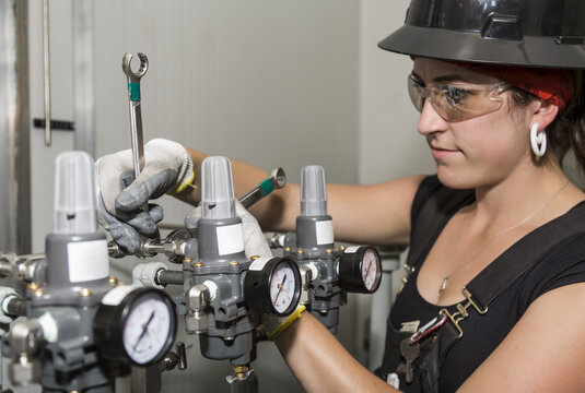 Female trades worker installing a fuel gas regulator; Innisfail, Alberta, Canada