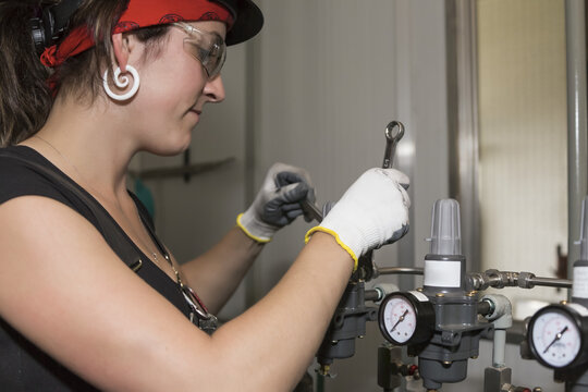 Female trades worker installing a fuel gas regulator; Innisfail, Alberta, Canada
