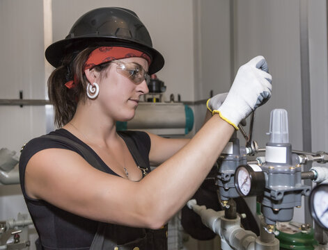 Female trades worker installing a fuel gas regulator; Innisfail, Alberta, Canada