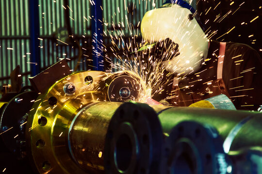 A journeyman pipe fitter welder grinding a flange butt weld on a separator unit in a fabrication plant; Innisfail, Alberta, Canada