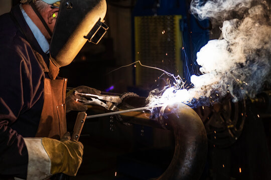 Welder is butt welding piping components in a fabrication plant; Innisfail, Alberta, Canada