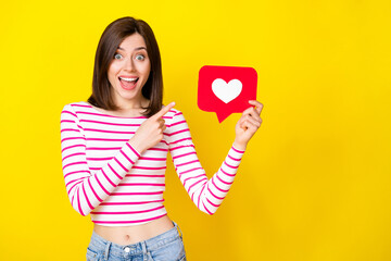 Photo of astonished millennial girl arm hold finger point red paper card sign empty space isolated on yellow color background