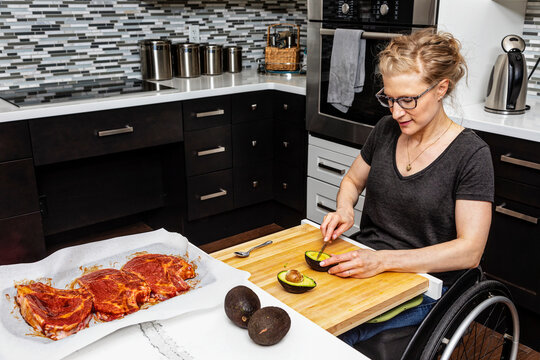 A paraplegic woman preparing a meal for her family in her kitchen while working from a wheelchair; Edmonton, Alberta, Canada