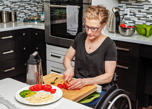 A paraplegic woman preparing a meal for her family in her kitchen while working from a wheelchair; Edmonton, Alberta, Canada