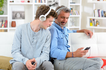 Two men with headphones looking at cellphone
