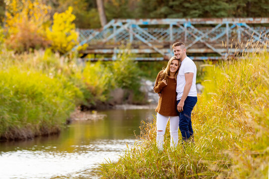 Husband and wife spending quality time together outdoors near a stream in a city park; Edmonton, Alberta, Canada