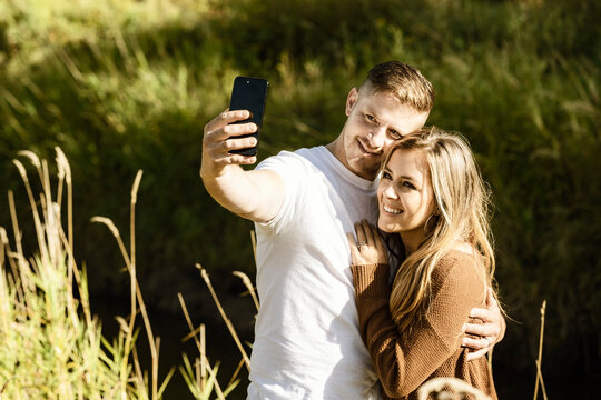 Husband and wife spending quality time together outdoors and taking a self-portrait in a city park; Edmonton, Alberta, Canada