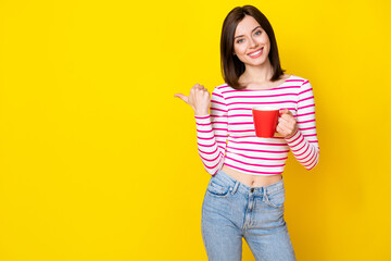 Photo of cheerful positive adorable girl with bob hairstyle wear striped shirt indicating empty space isolated on yellow color background