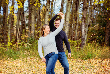 A married couple spending quality time together and dancing together outdoors in a city park during the fall season; St. Albert, Alberta, Canada