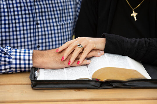 A mature couple sharing devotional time together and studying the bible at a picnic table on a warm fall day in a city park; St. Albert, Alberta, Canada