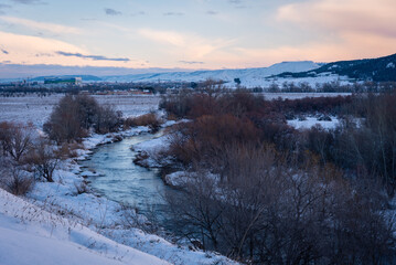 Beautiful snowy landscape after a snowstorm with a river and trees without leaves at sunset in winter, Torrejon de Ardoz, Madrid, Spain