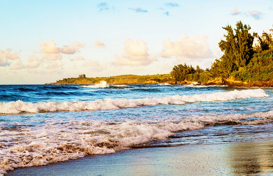 Waves roll into the beach with a view of the coastline at sunset on D.T. Fleming Beach; Kapalua, Maui, Hawaii, United States of America