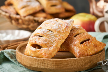 Hand pies. Mini puff pastry or hand pies stuffed with apple and sprinkle sugar powder in wooden plate. Homemade pie snack with crust for breakfast rustic photo.  Copy space.