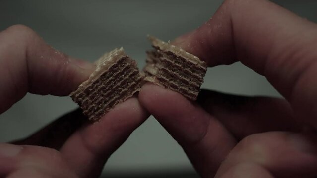 Hands break a bar of chocolate. Closeup.