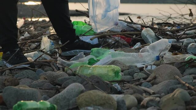 Man picks up plastic bottles in trash bag on the beach in Batumi city. Volunteer collecting recycling garbage. Environmental pollution concept