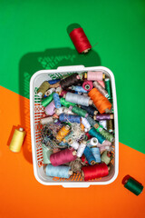 A box with multi colored coins of different threads on a colored background