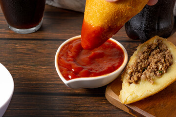 dipping coxinha on the ketchup sauce. traditional brazilian fried coxinha snack fast food