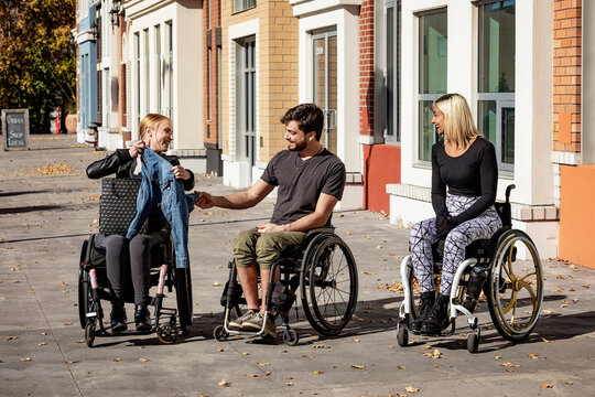 Three young paraplegic friends spending time together shopping outside in a city area; Edmonton, Alberta, Canada