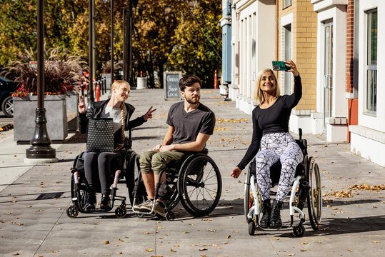 Three young paraplegic friends spending time together outside shopping and taking pictures in a city area; Edmonton, Alberta, Canada