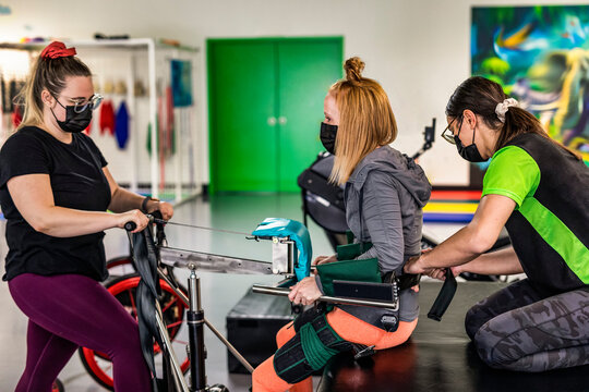 A paraplegic woman working out using an assisted walking machine with her trainers; Edmonton, Alberta, Canada