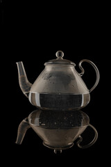 Beautiful transparent glass teapot close-up isolated on black background.