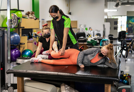A paraplegic woman working on hip flexion while her trainer does physical queuing: Edmonton, Alberta, Canada
