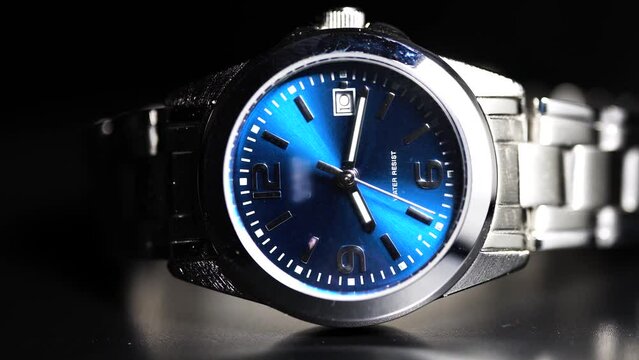 silver watch of blue interface on dark background, play with light