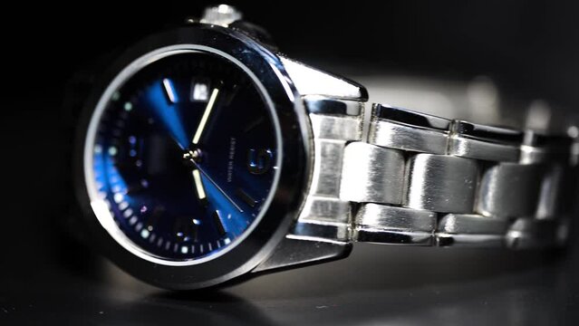 rolling silver watch of blue interface on dark background, play with light