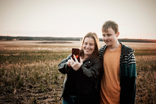 A mother with epilepsy taking a self-portrait with her son who has Aspberger Syndrome in a field on a farm after harvest; Westlock, Alberta, Canada